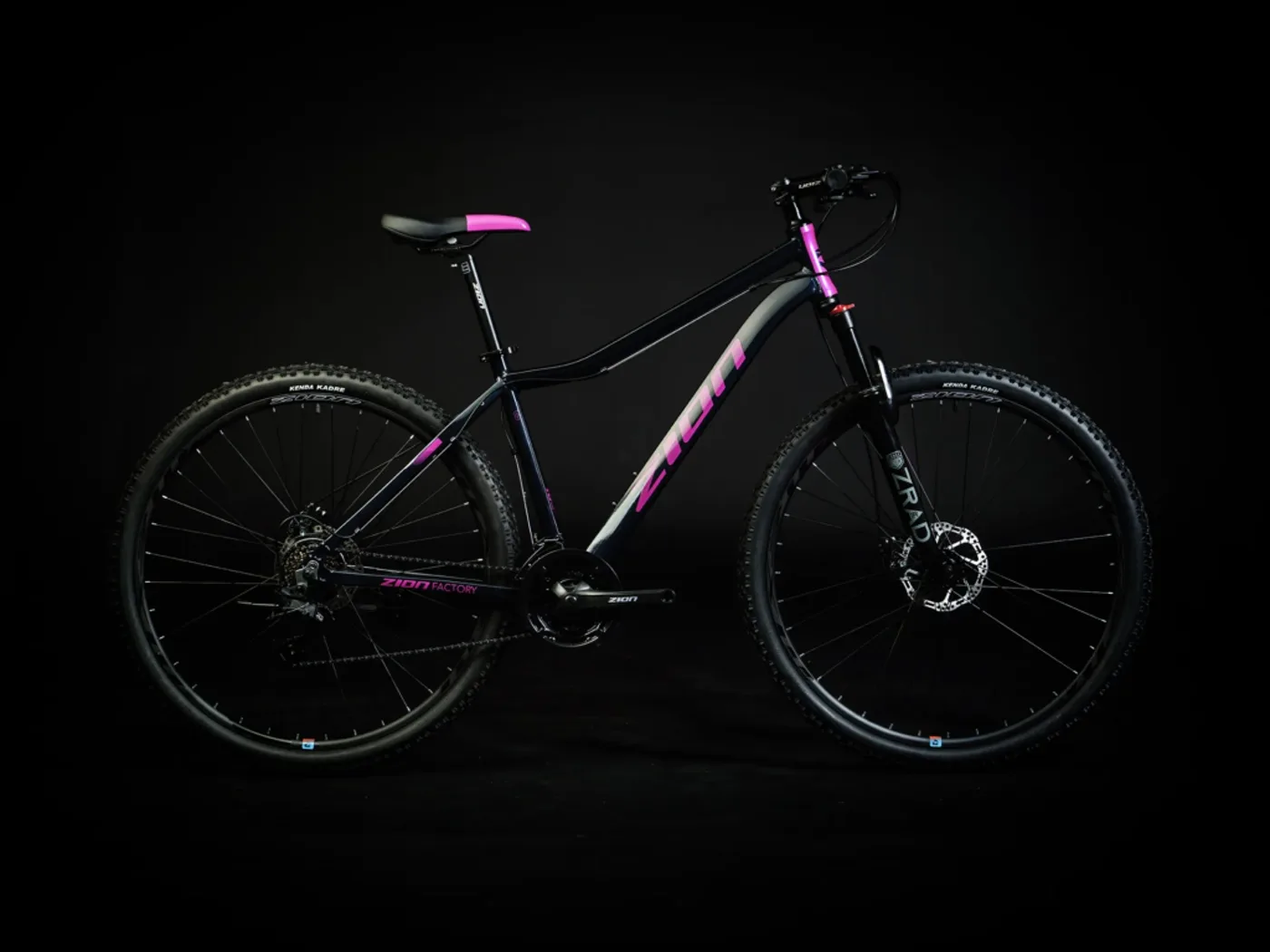 Bicicleta Zion Breva negra con detalles rosas, de perfil sobre fondo negro